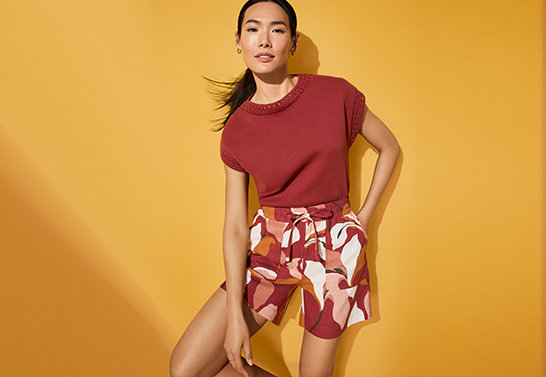 a woman posing with left hand on hip and right hand touching her neck